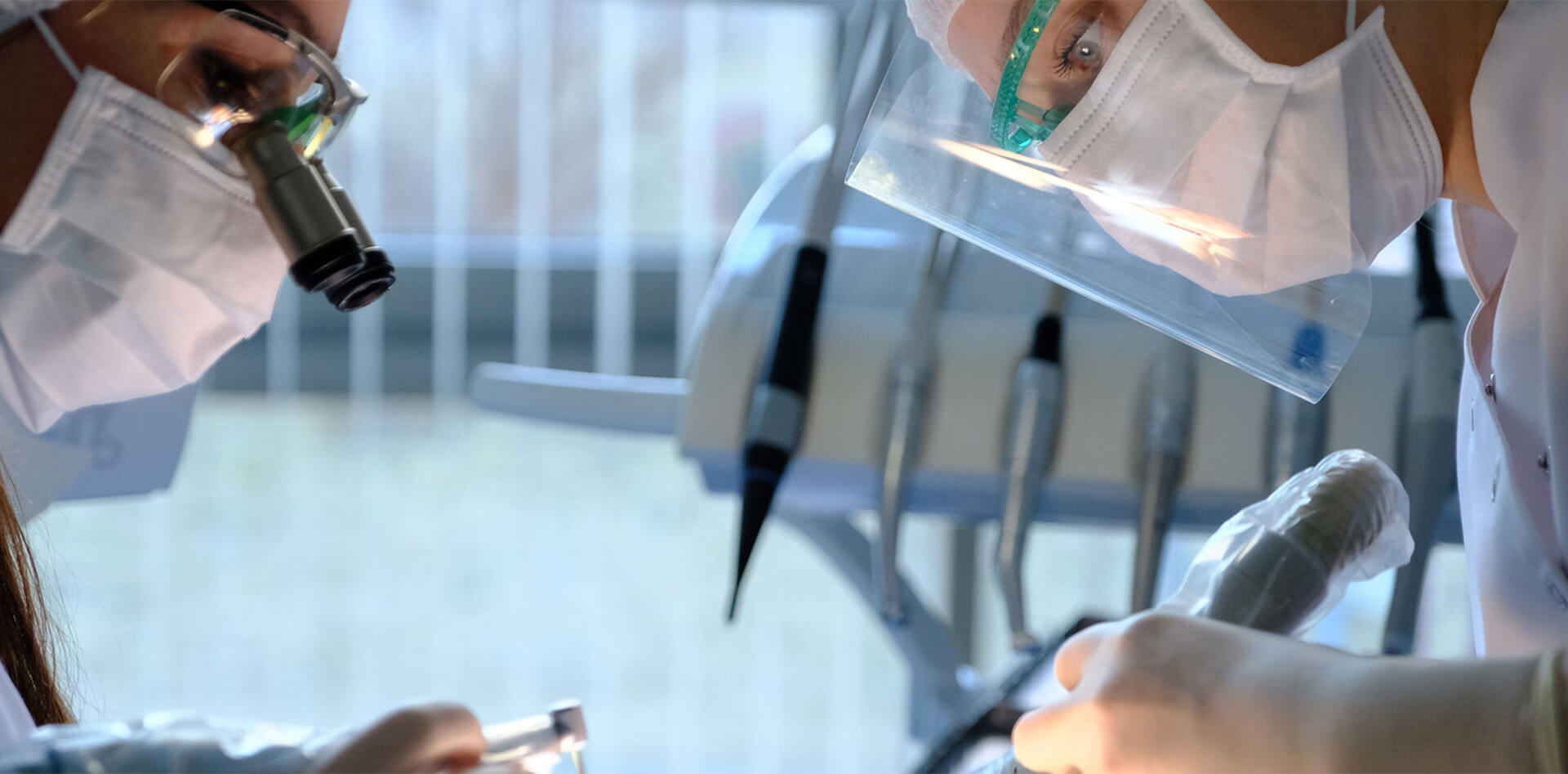 Dental professionals performing oral surgery procedures, equipped with magnifying glasses and masks, in a modern dental office setting, emphasizing patient care and advanced technology.
