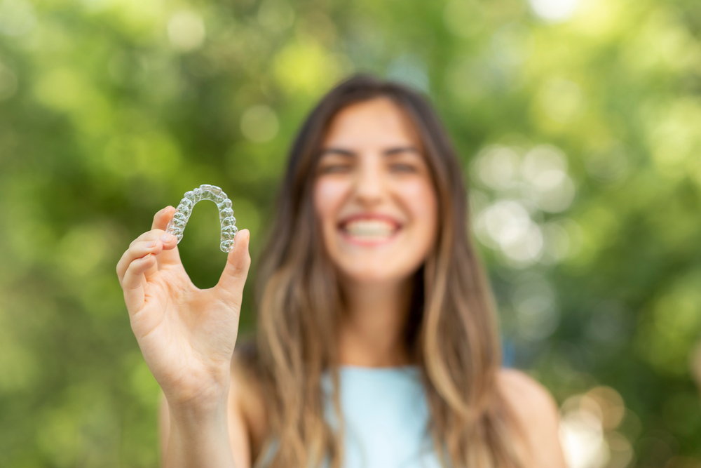 young patient holding her Invisalign aligners